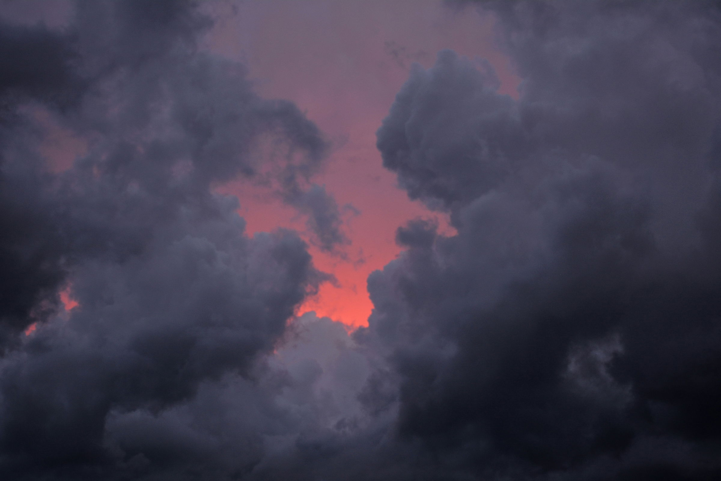 Abstract artwork featuring horizontal bands of vibrant colors including pink, purple, red, orange, and black, resembling a digital glitch or color spectrum pattern of dark clouds.