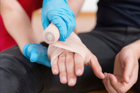 A doctor is bandaging a young man's hand