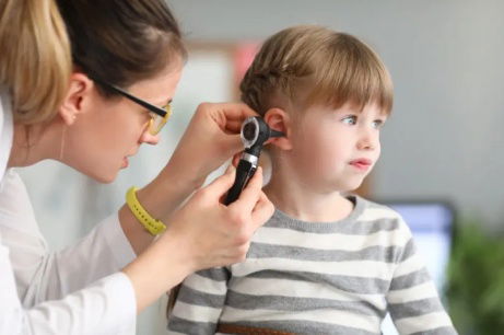 A doctor is checking a little girl's ear.
