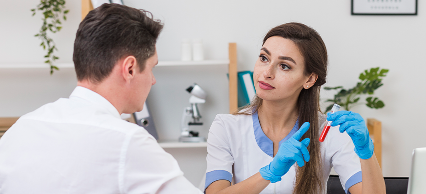 A physician listens to the heartbeat of a worker holding his yellow hard hat.