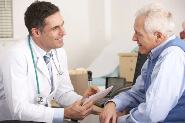 An elder man is carefully listening to his smiling and friendly doctor