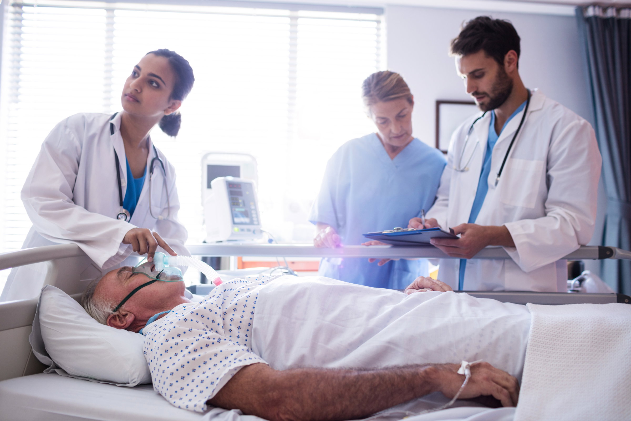 A physician listens to the heartbeat of a worker holding his yellow hard hat.