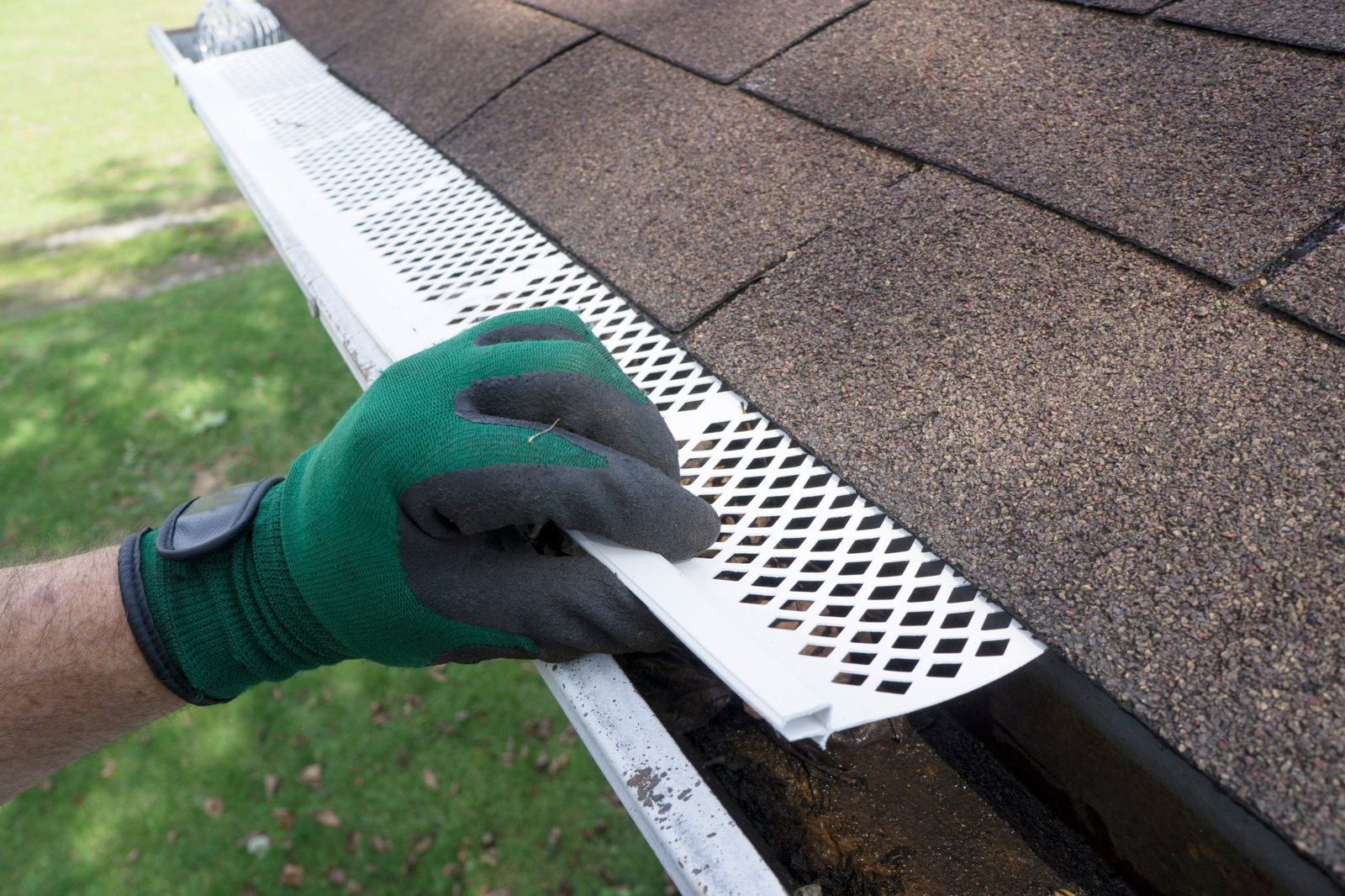    Gloved hand installing a white gutter guard on a Minneapolis-area home