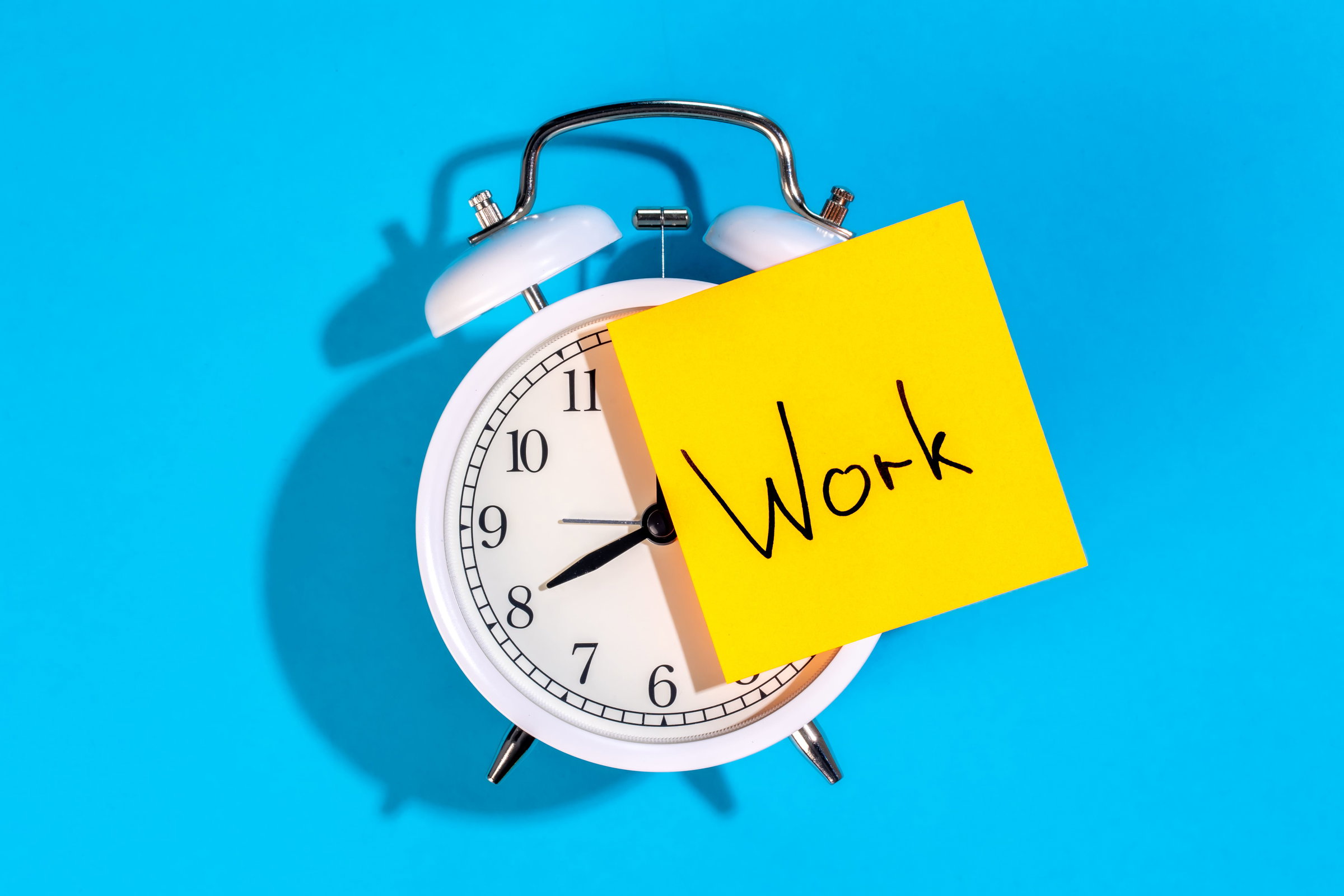 Illustration d'un réveil réglé sur 8h00, heure d'embauche pour aller au travail. Sur un post-it, le mot travail est inscrit en anglais.