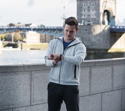 Image d'un homme anglais qui prend du temps pour lui grâce à la semaine de 4 jours qui a été mise en place dans son entreprise. Il se tient devant le tower bridge.