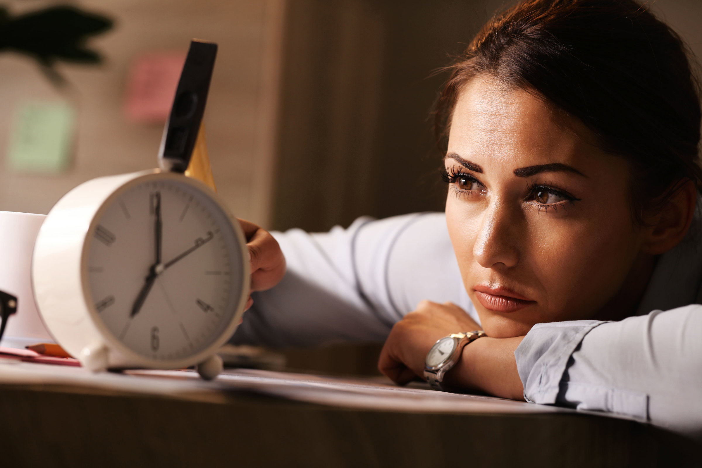 Image d'une femme qui regarde fixement un réveil. Elle représente la possibilité de réduire le temps de travail en France et de passer à la semaine de 4 jours sur 35h