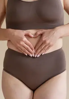 Femeie cu mâinile pe abdomen – simptomatologie posibilă în prolapsul genital