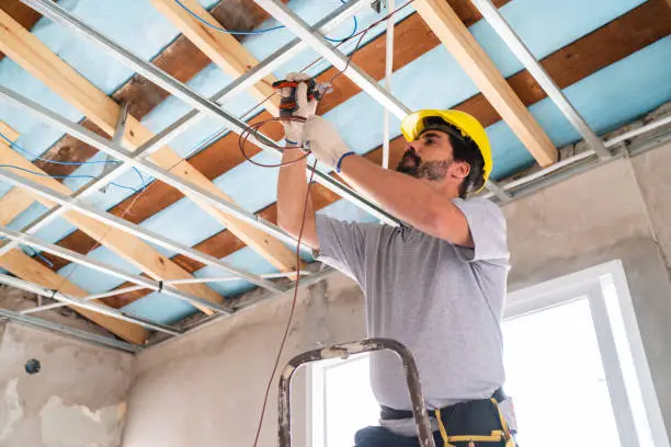 Licensed Spokane electrician safely installing new wiring in a residential ceiling 
