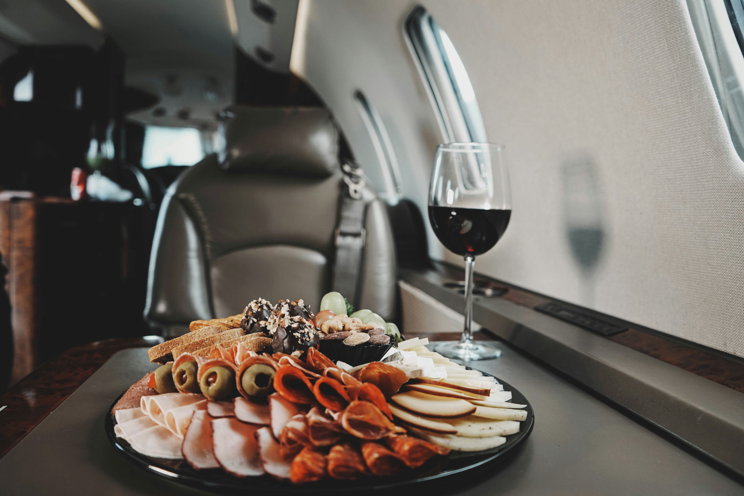 Charcuterie platter and glass of red wine set on a private jet cabin table.