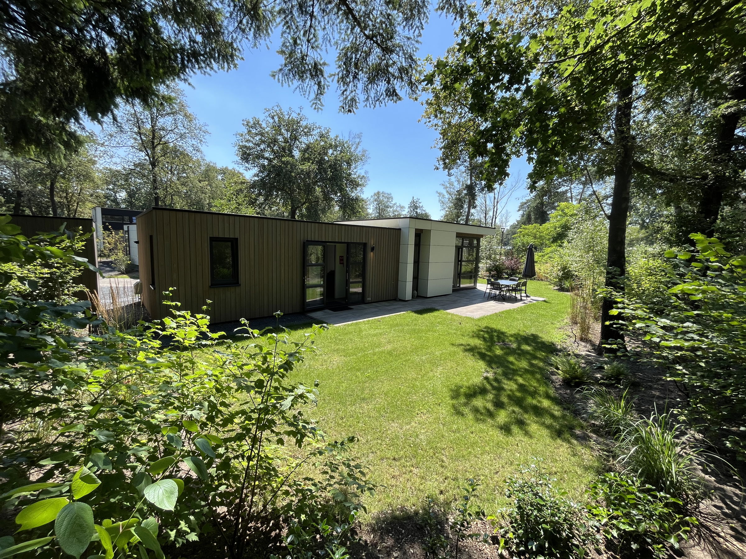 Private garden with sunny terrace, outdoor dining table and chairs surrounded by greenery