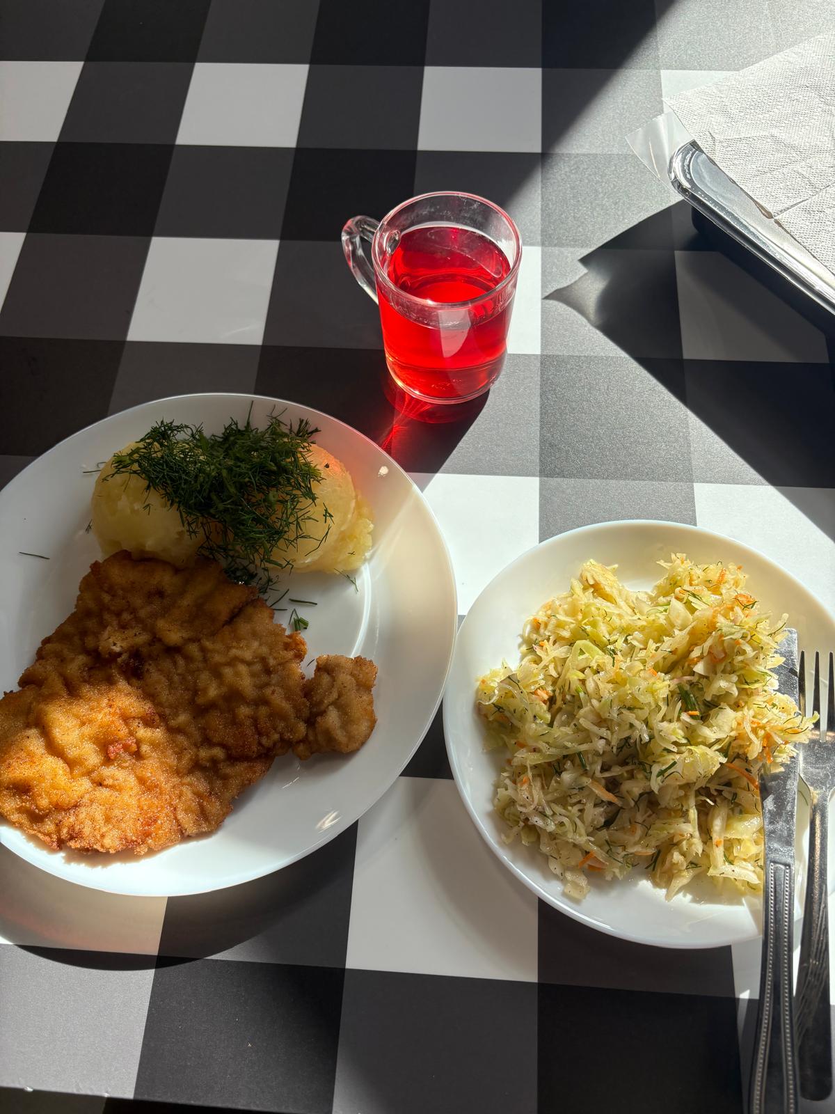 A classic Polish dinner with breaded cutlet, potatoes with dill, cabbage salad and compote in Warsaw.